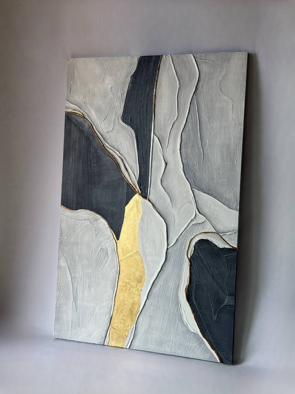 sombra y oro, 90×140 cm — White and graphite forms split by a vein of gold leaf running the full height of the canvas.